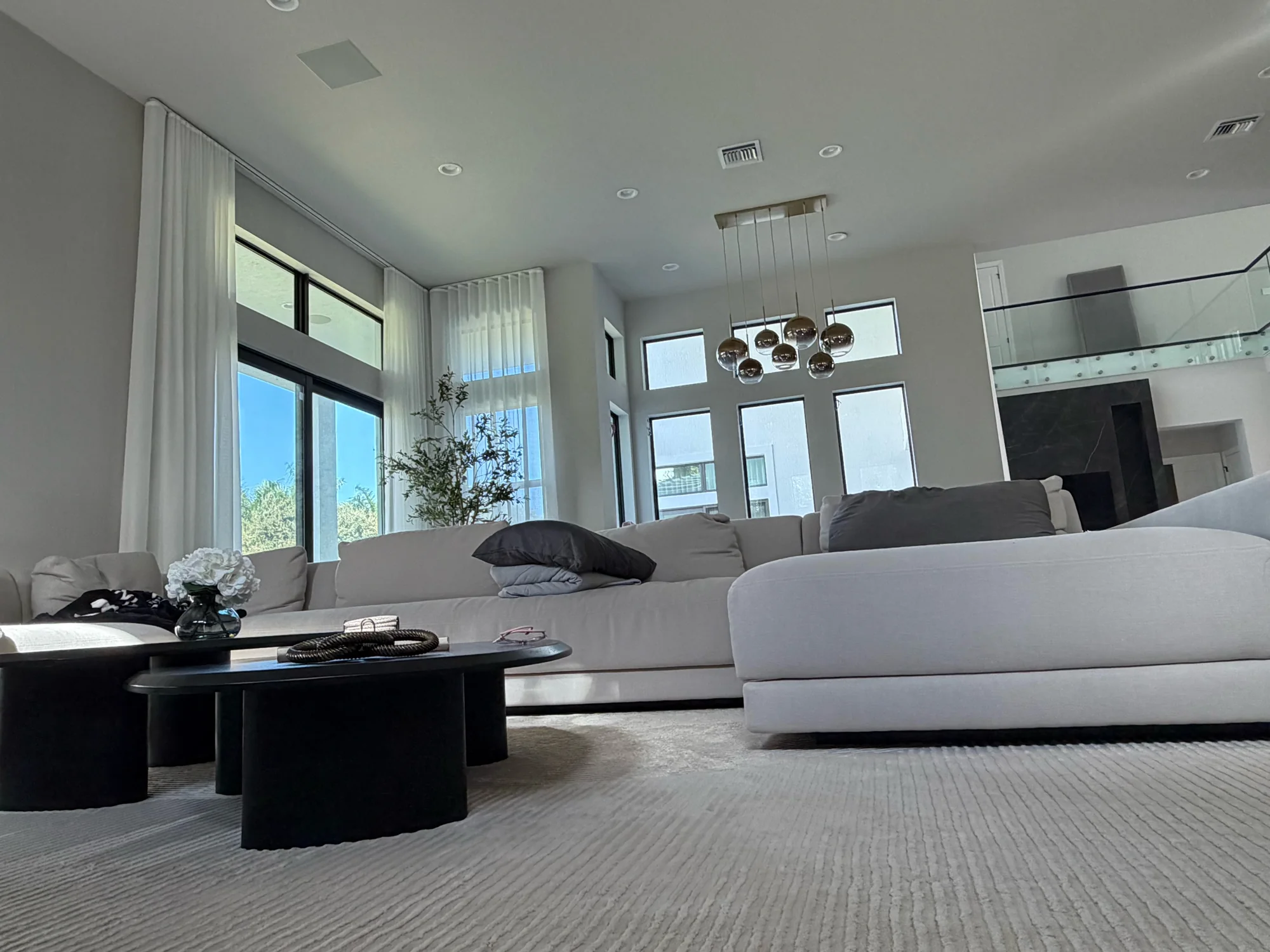 Floor-to-ceiling white sheer drapery framing a double-height living room