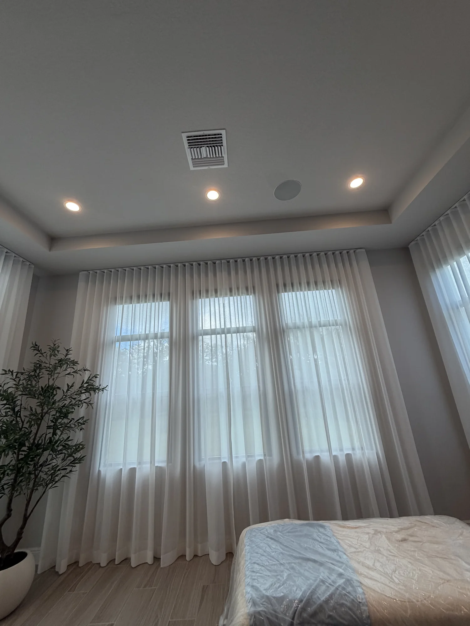 Full-height sheers soften daylight across the bedroom windows.