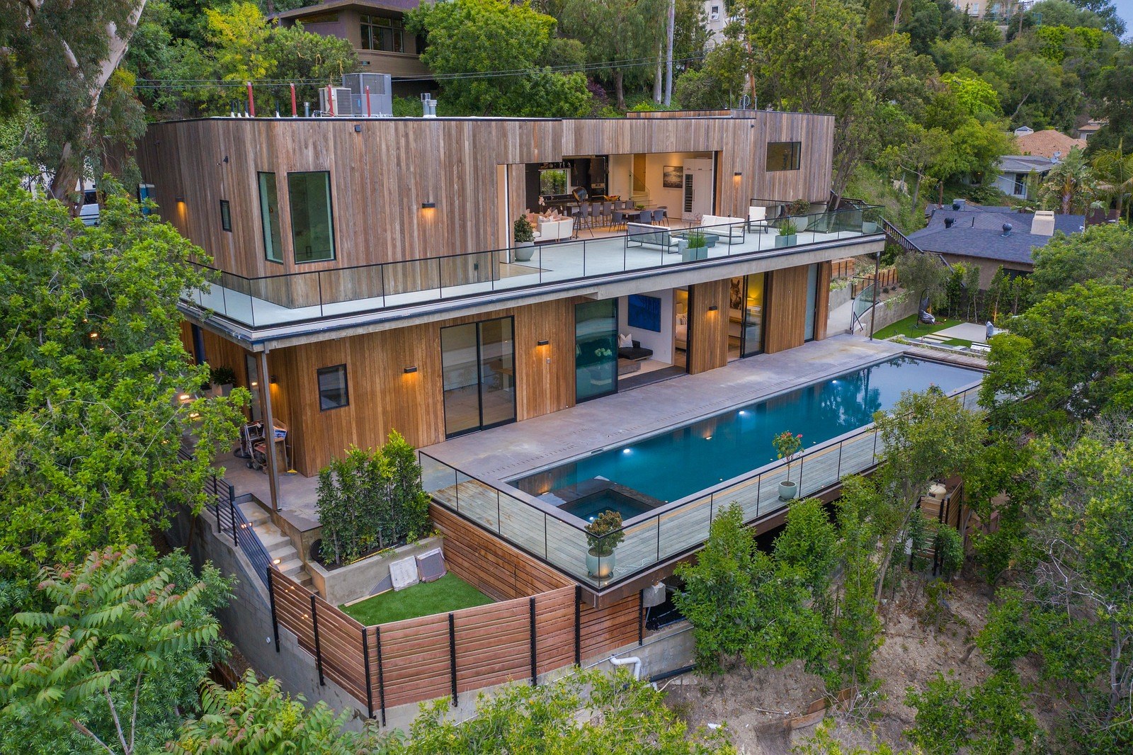 Aerial view of the Dixie Canyon residence in Sherman Oaks, a two-level home stepping down a wooded hillside lot with a pool terrace over the slope