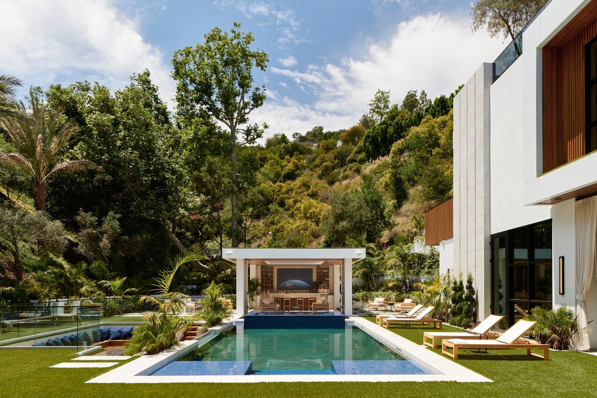Mandeville Canyon home with pool and cabana, the wooded canyon hillside rising behind the house