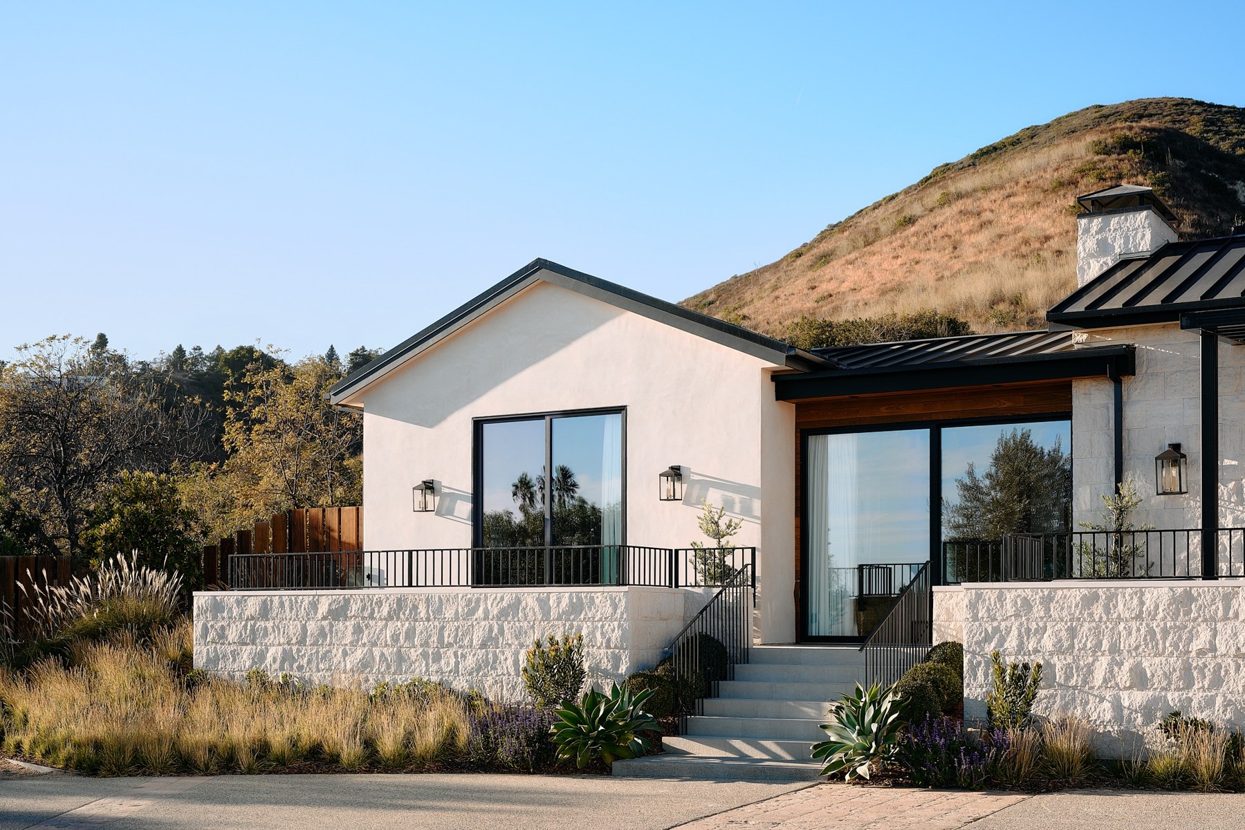 Malibu home built into the hillside, the bare slope of the Santa Monica Mountains rising directly behind it