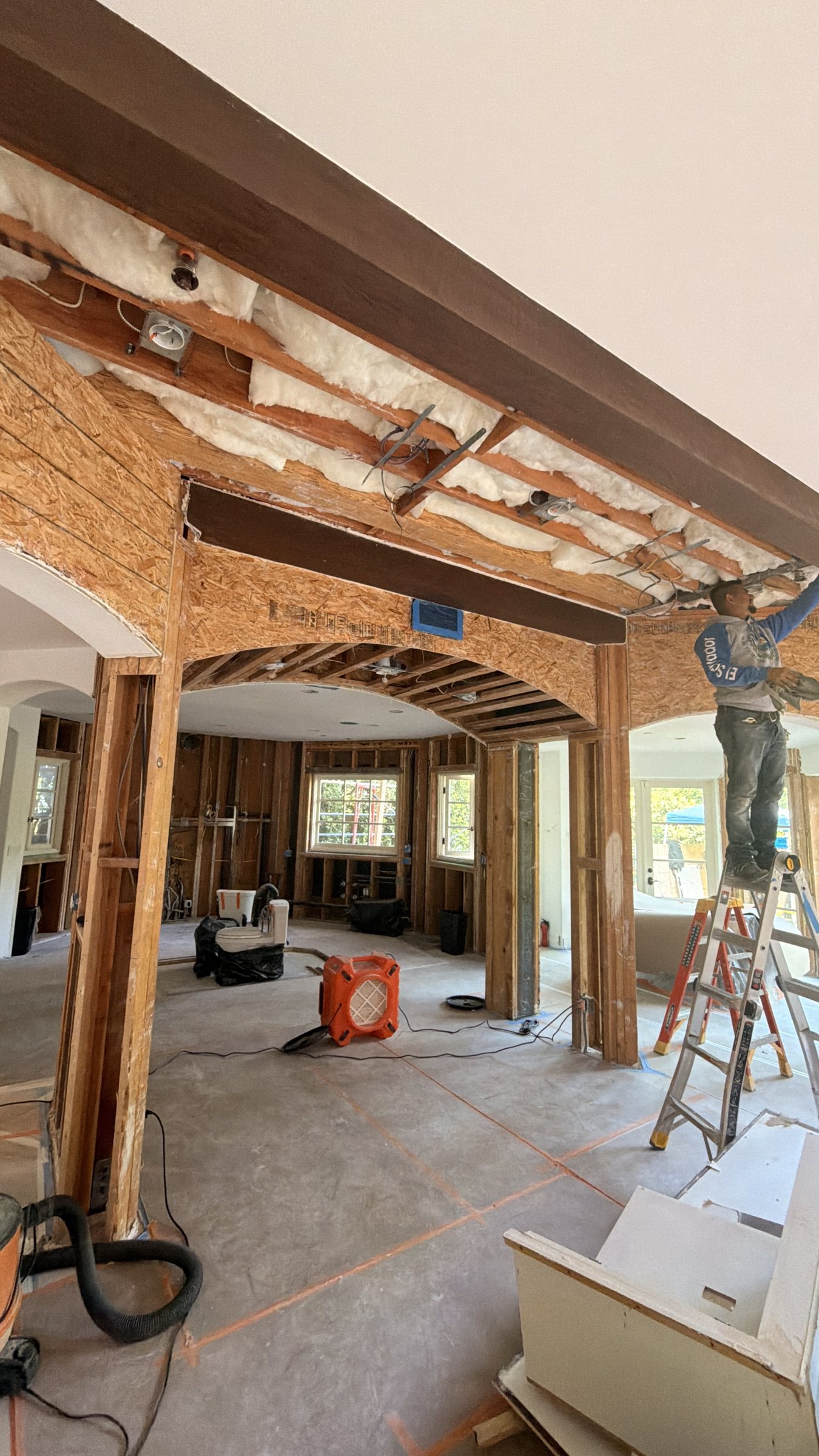Inside a Santa Monica home mid-remodel: new steel beam and framing where a wall came out, crew at work