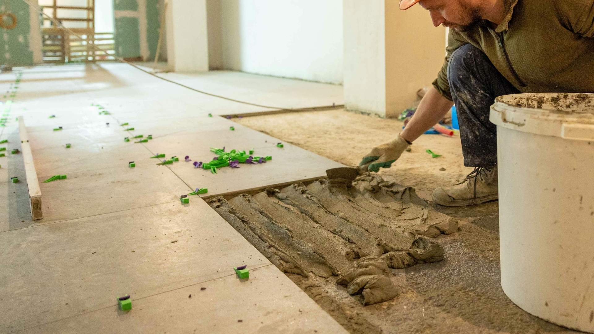 Professional floor tile installation using spacers and mortar during a home renovation project.