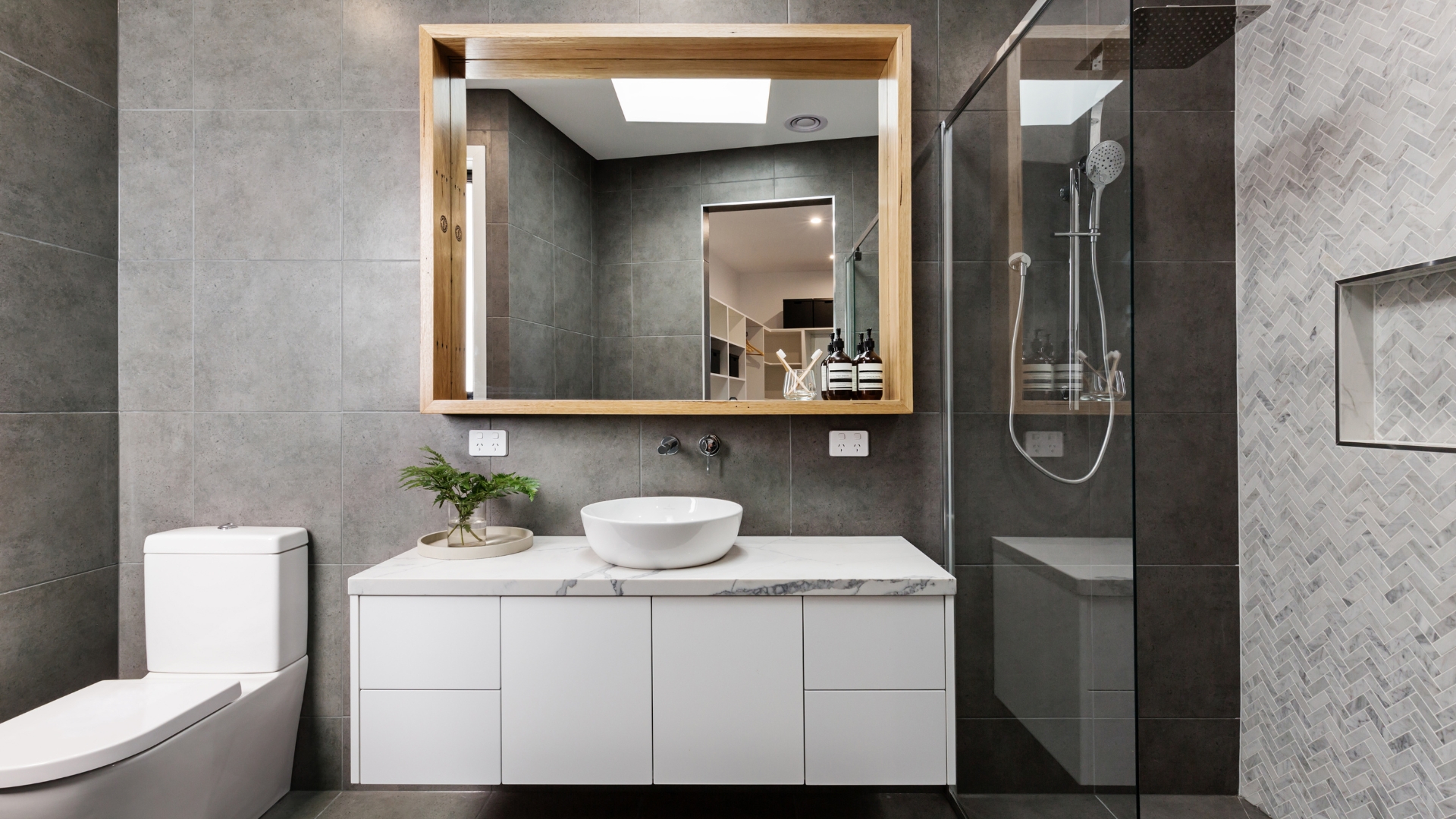 Modern bathroom remodel with a wooden-framed mirror, white vanity, and glass shower enclosure