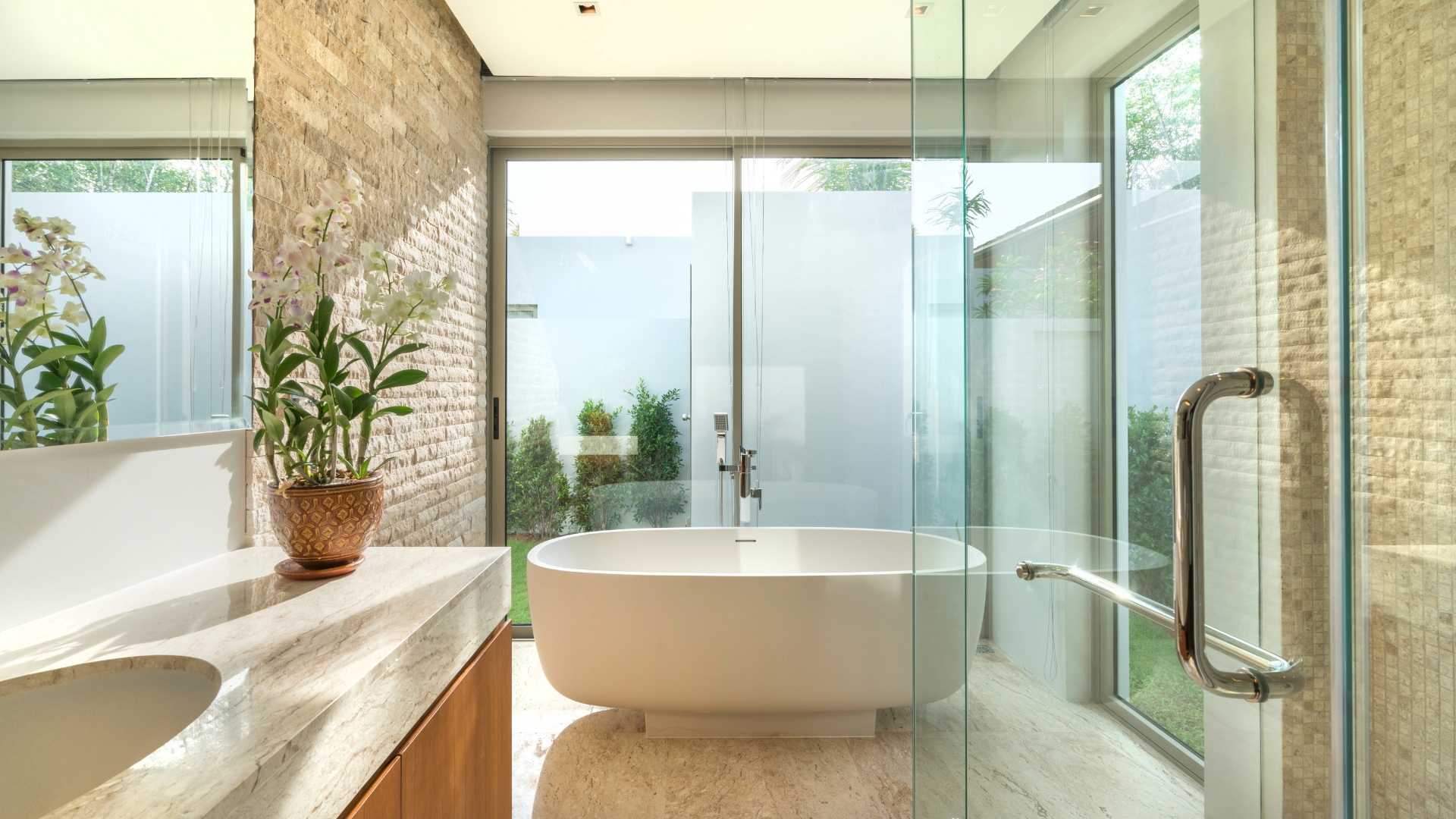 Full bathroom remodel with freestanding tub, glass shower, and natural stone finishes.