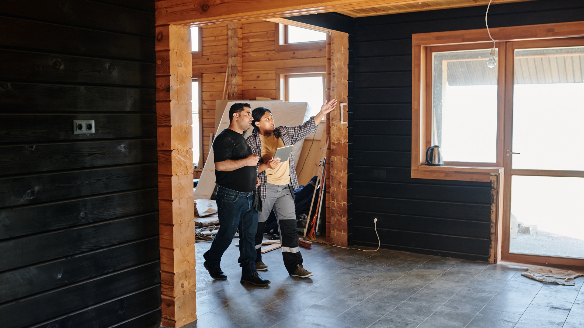 General contractor for home remodel discussing progress inside a partially remodeled space with exposed wood and tile flooring