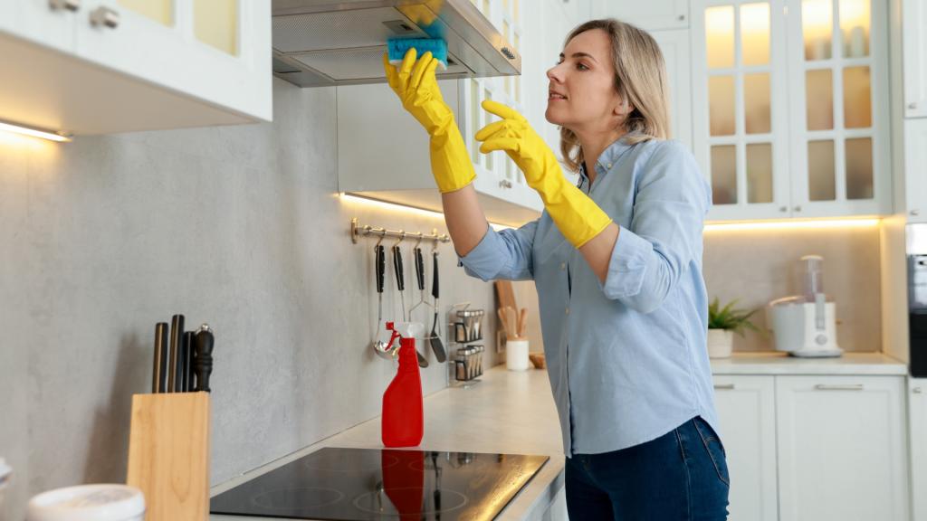 A homeowner cleaning the range hood as part of home maintenance after remodeling