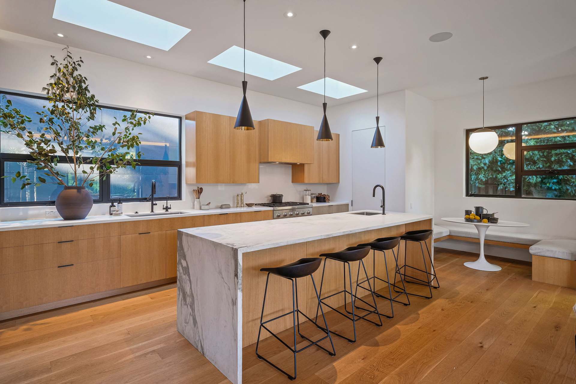 Modern kitchen with skylights, waterfall island, and wood cabinets.