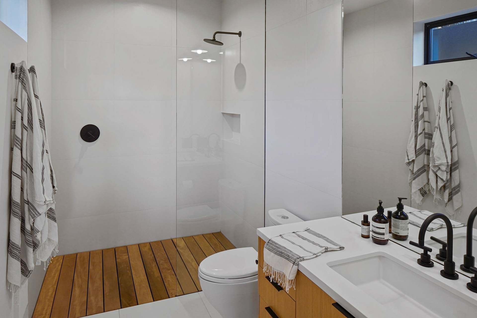 Walk-in shower bathroom with a wood shower floor and custom vanity.
