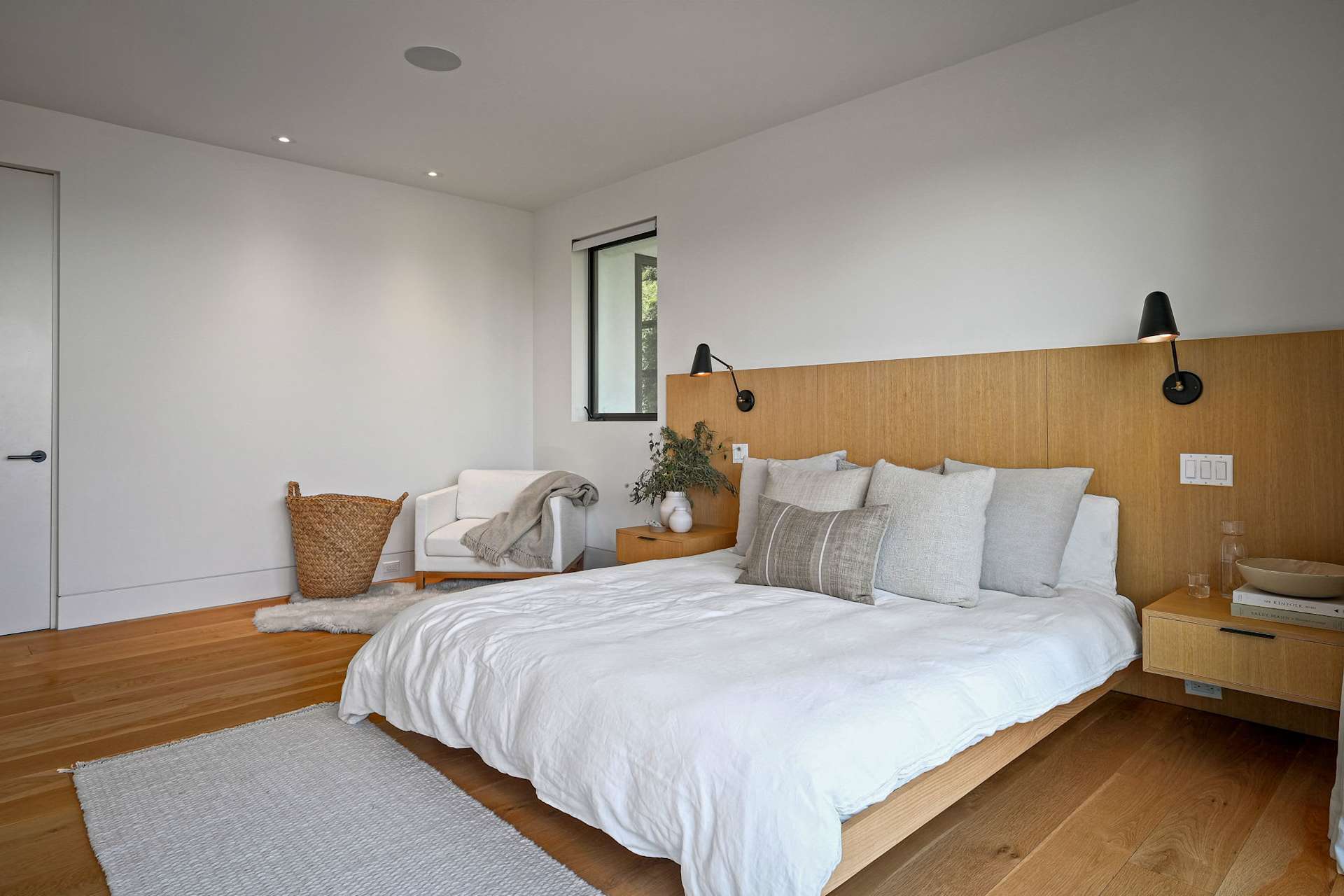 Modern bedroom with a custom headboard and hardwood flooring.