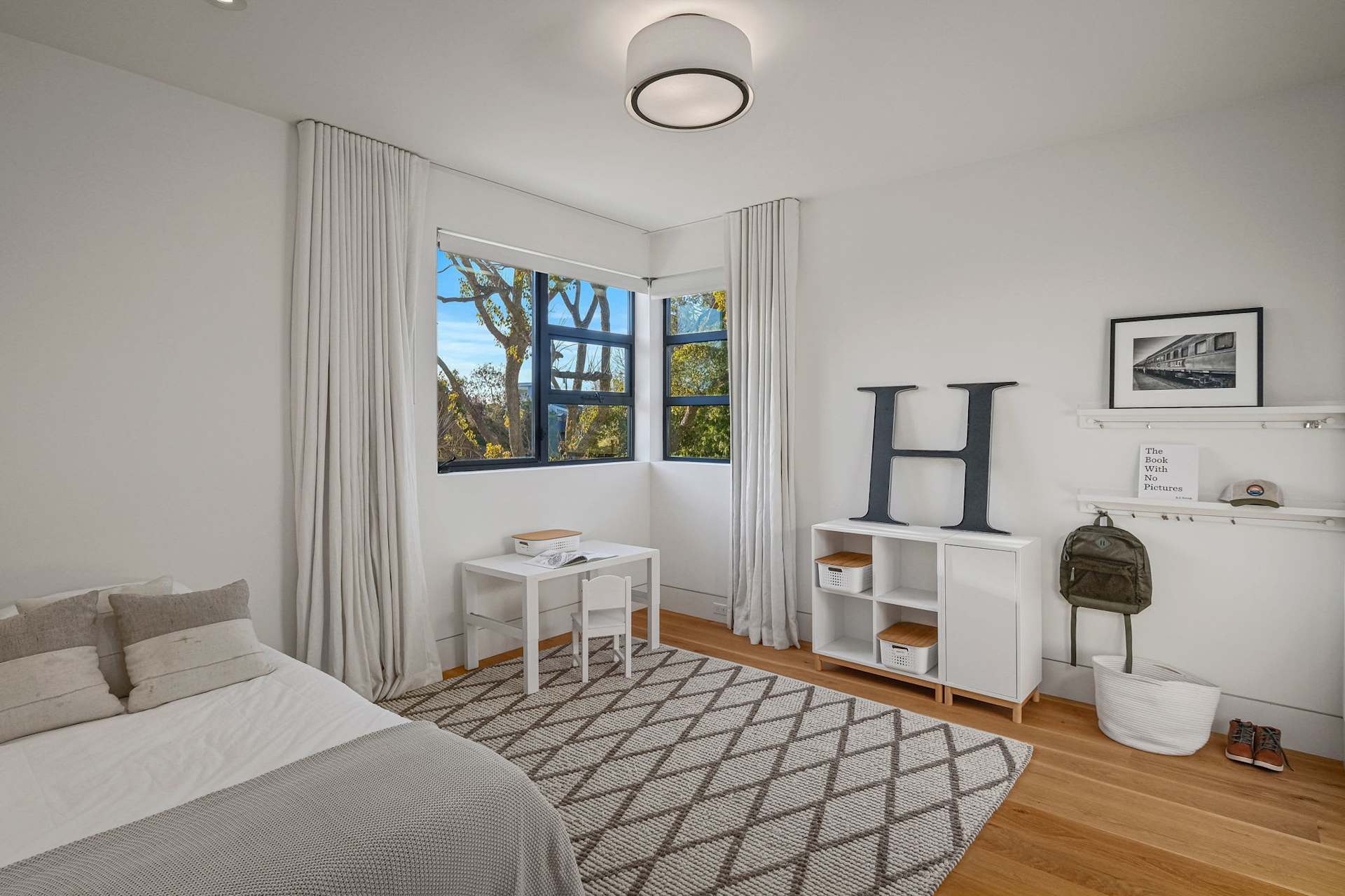 Kids' bedroom with corner windows and modern storage furniture.