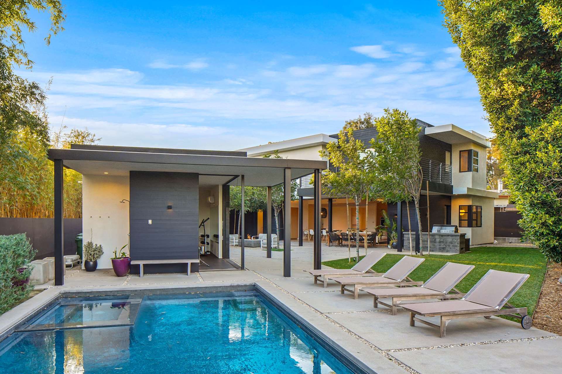 Backyard pool and detached ADU on home with lounge chairs and modern outdoor living space.