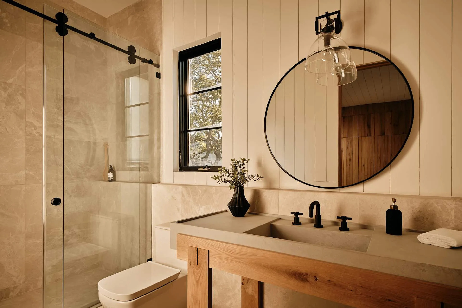 Modern bathroom with floating vanity, stone shower and round mirror