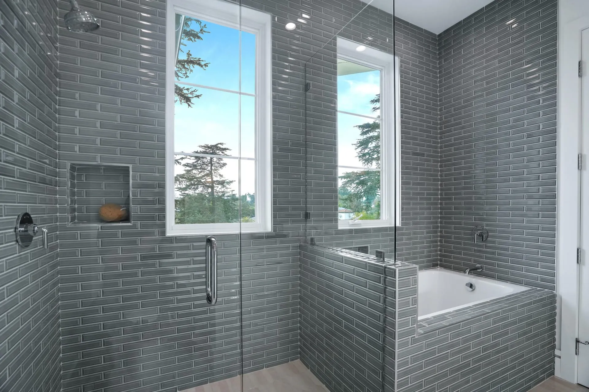 Gray-tiled bathroom with a glass shower and built-in tub