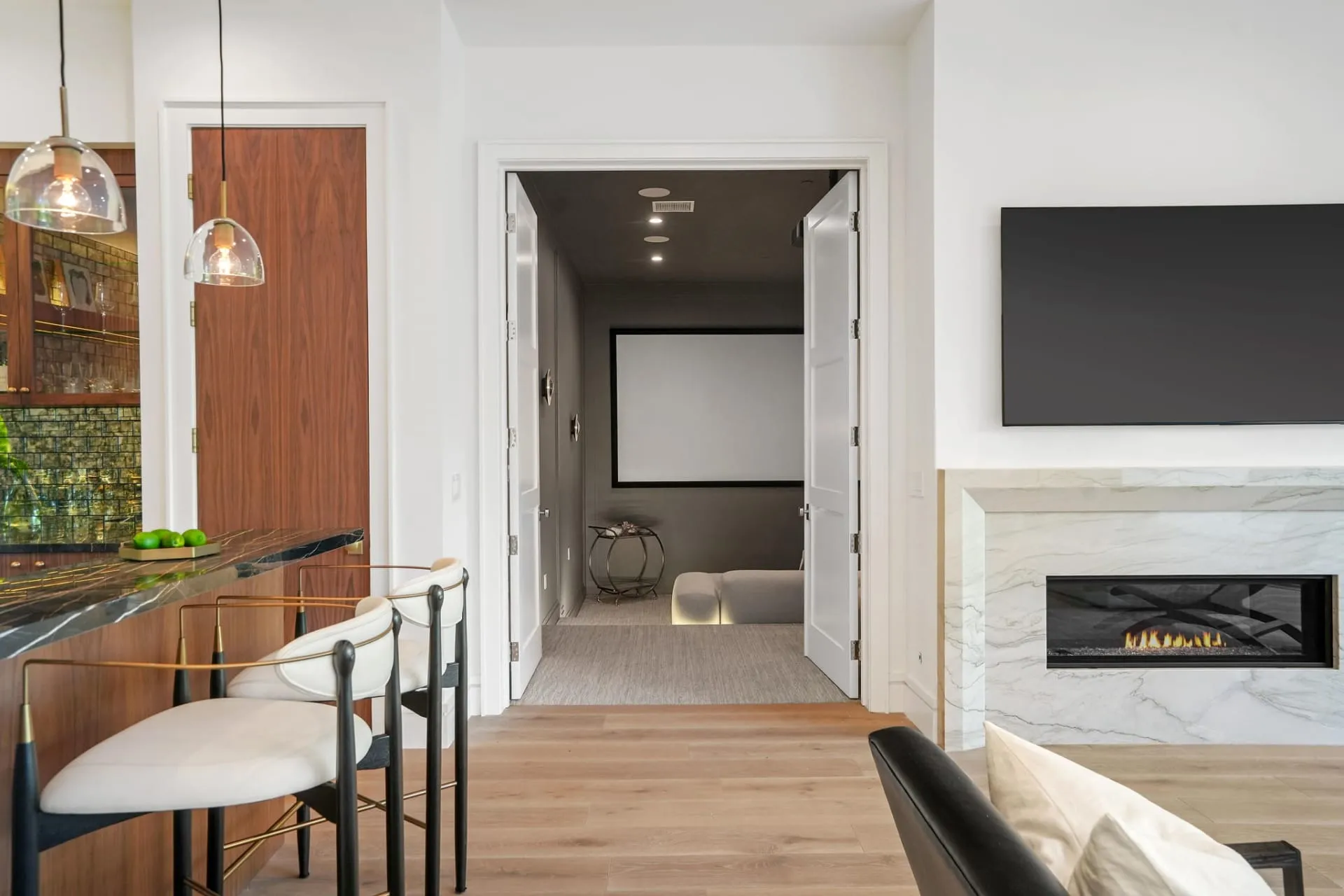 Wet bar and fireplace beside a doorway leading to the home theater