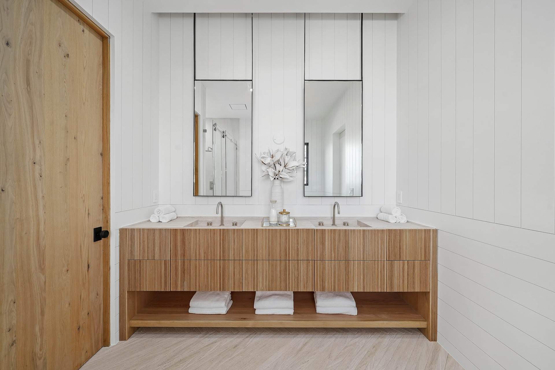 Elegant primary bathroom with double vanity, wood cabinetry, tall mirrors, and modern finishes