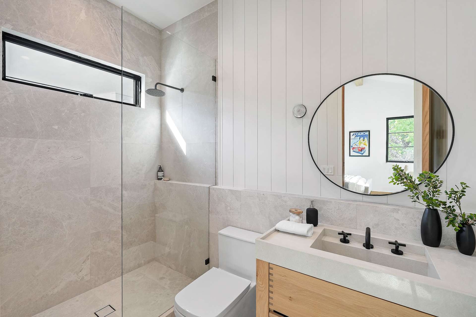 Modern secondary bathroom with walk in shower, round mirror, stone surfaces, and custom wood vanity