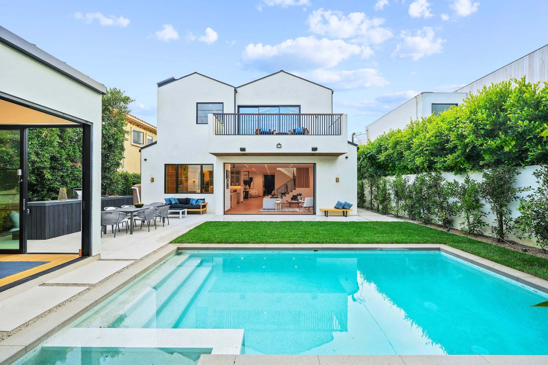 Luxury backyard with swimming pool, manicured lawn, outdoor seating, and modern new construction home