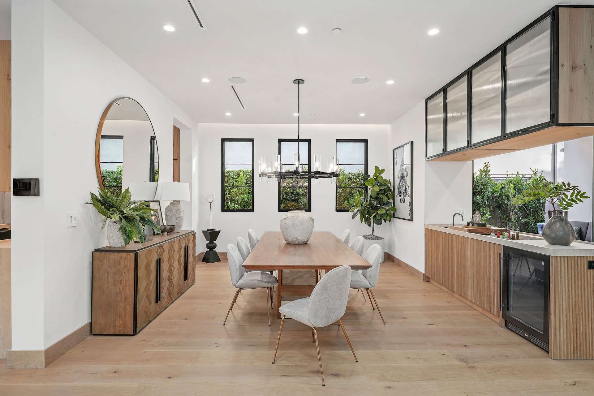 Modern dining room with wood table, upholstered chairs, designer chandelier, and clean contemporary finishes