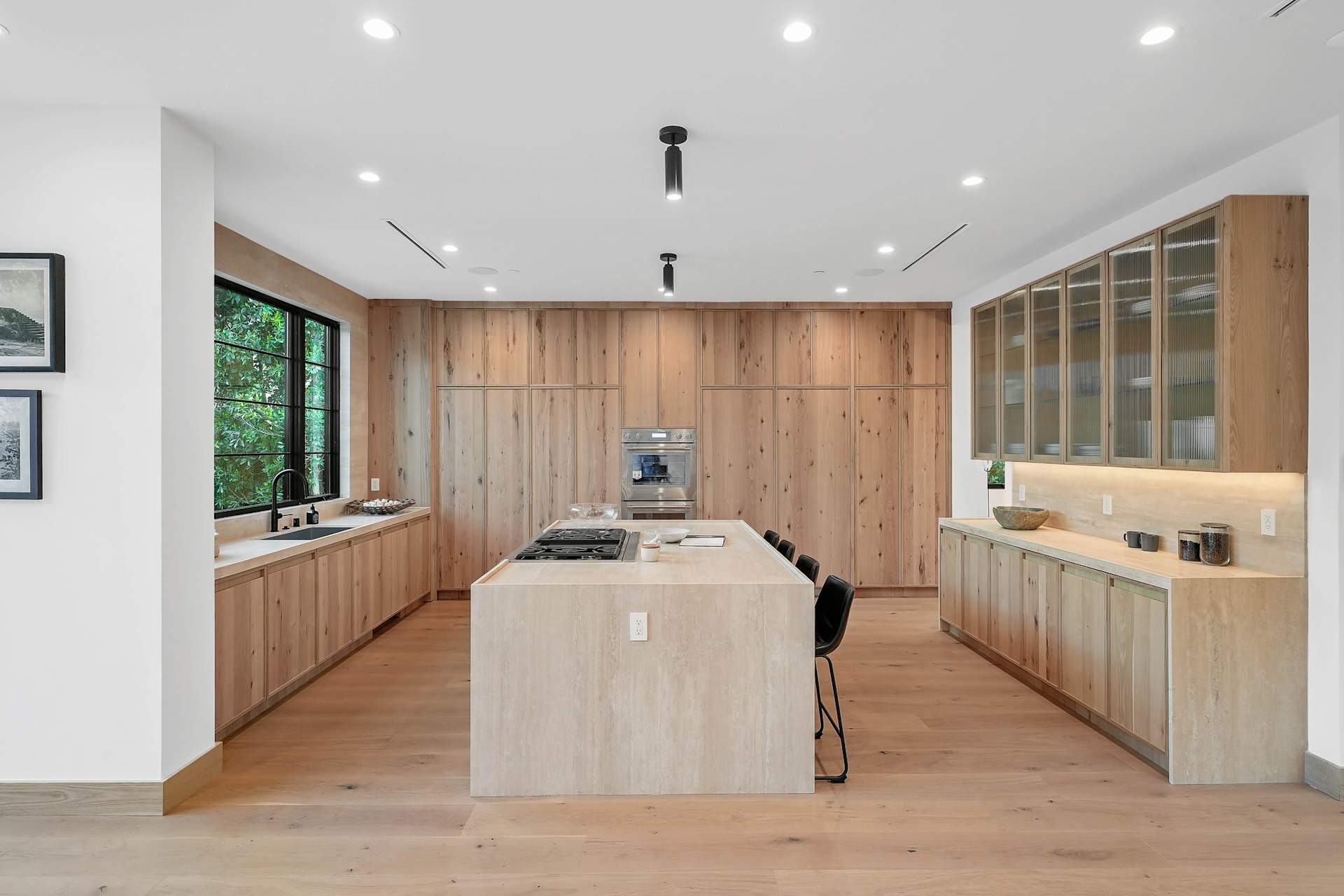 Contemporary kitchen with oversized island, custom wood cabinetry, stone countertops, and premium appliances