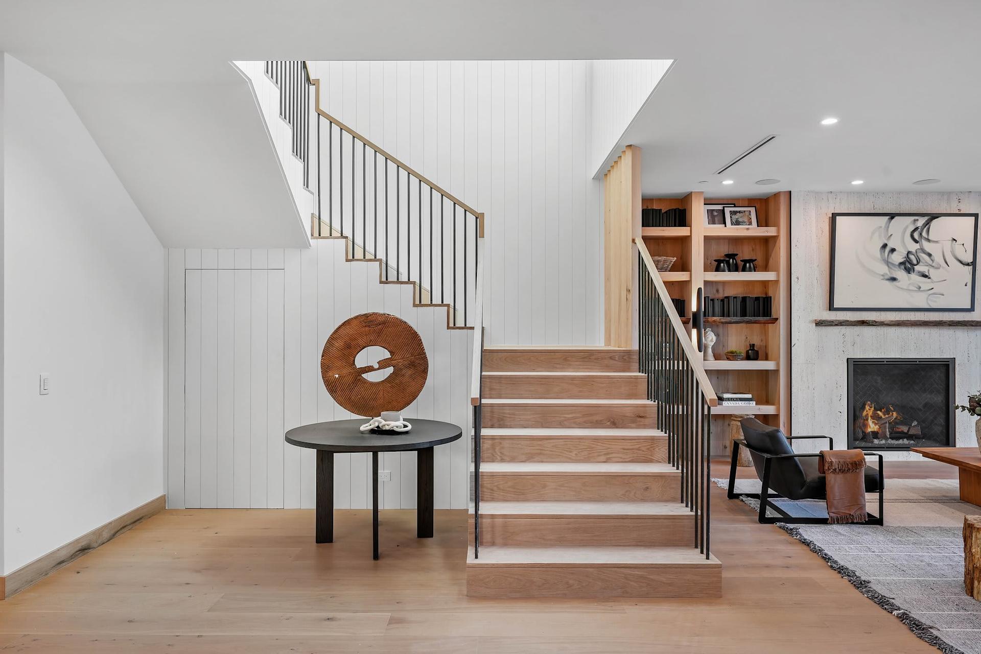 Modern custom staircase with wood treads, black metal railing, and open concept living area