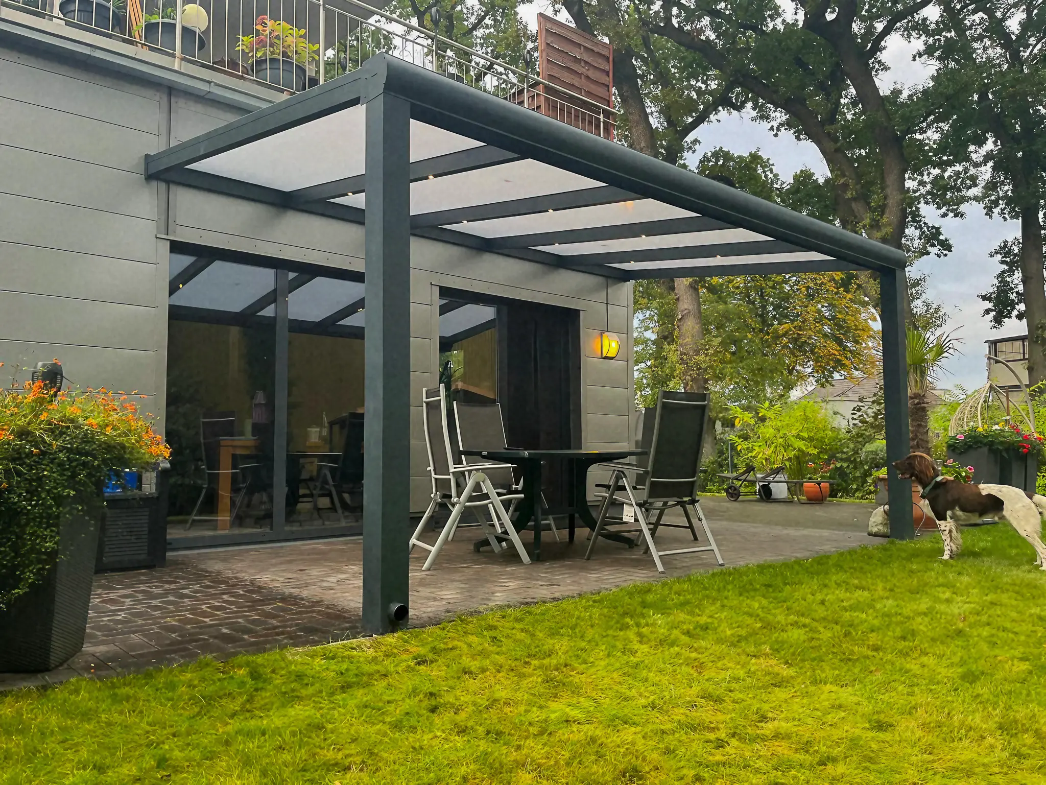 Moderne Terrassenüberdachung mit Gartenmöbeln und grünem Rasen