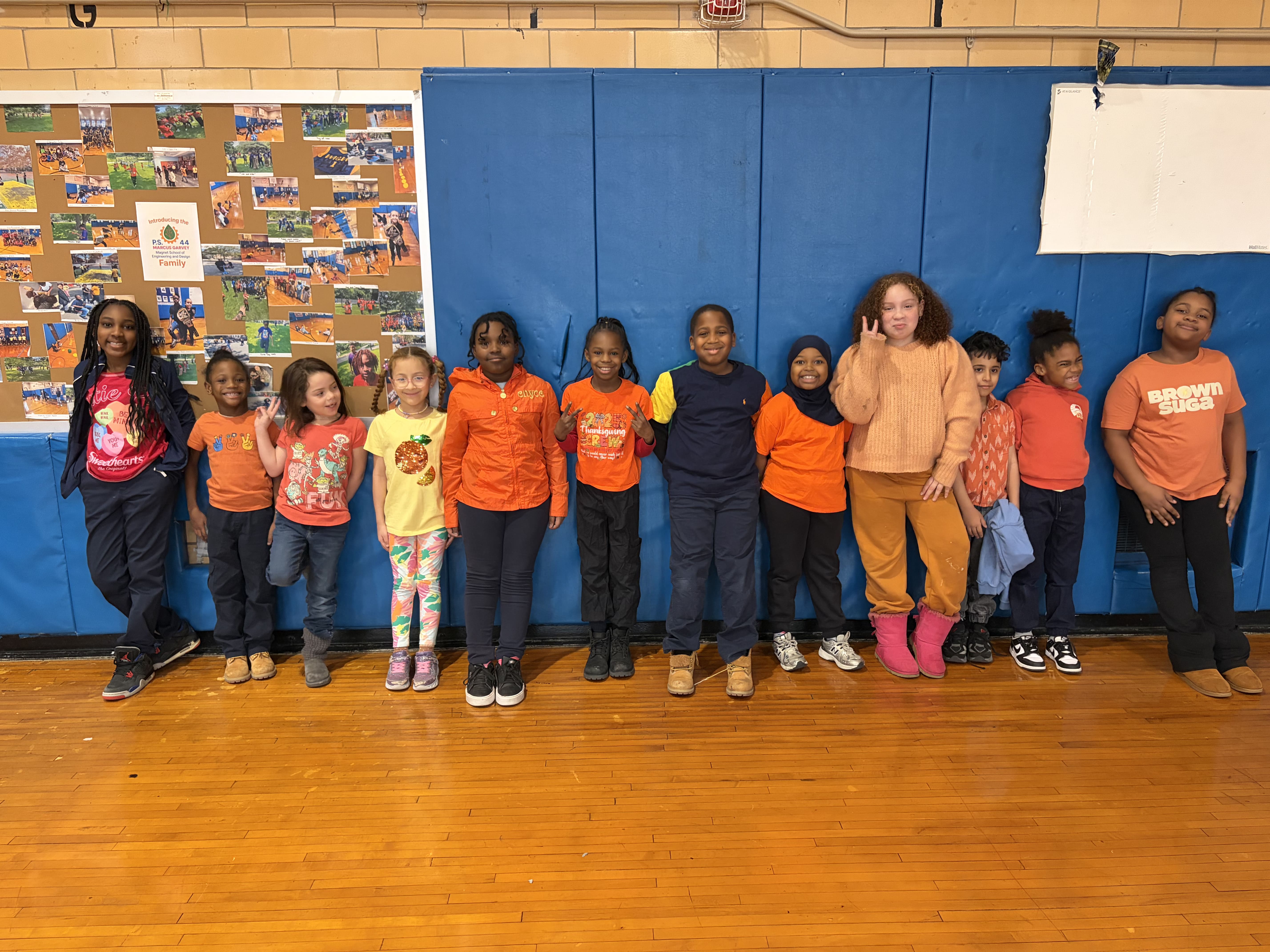 Students wearing orange pose together in school gymnasium