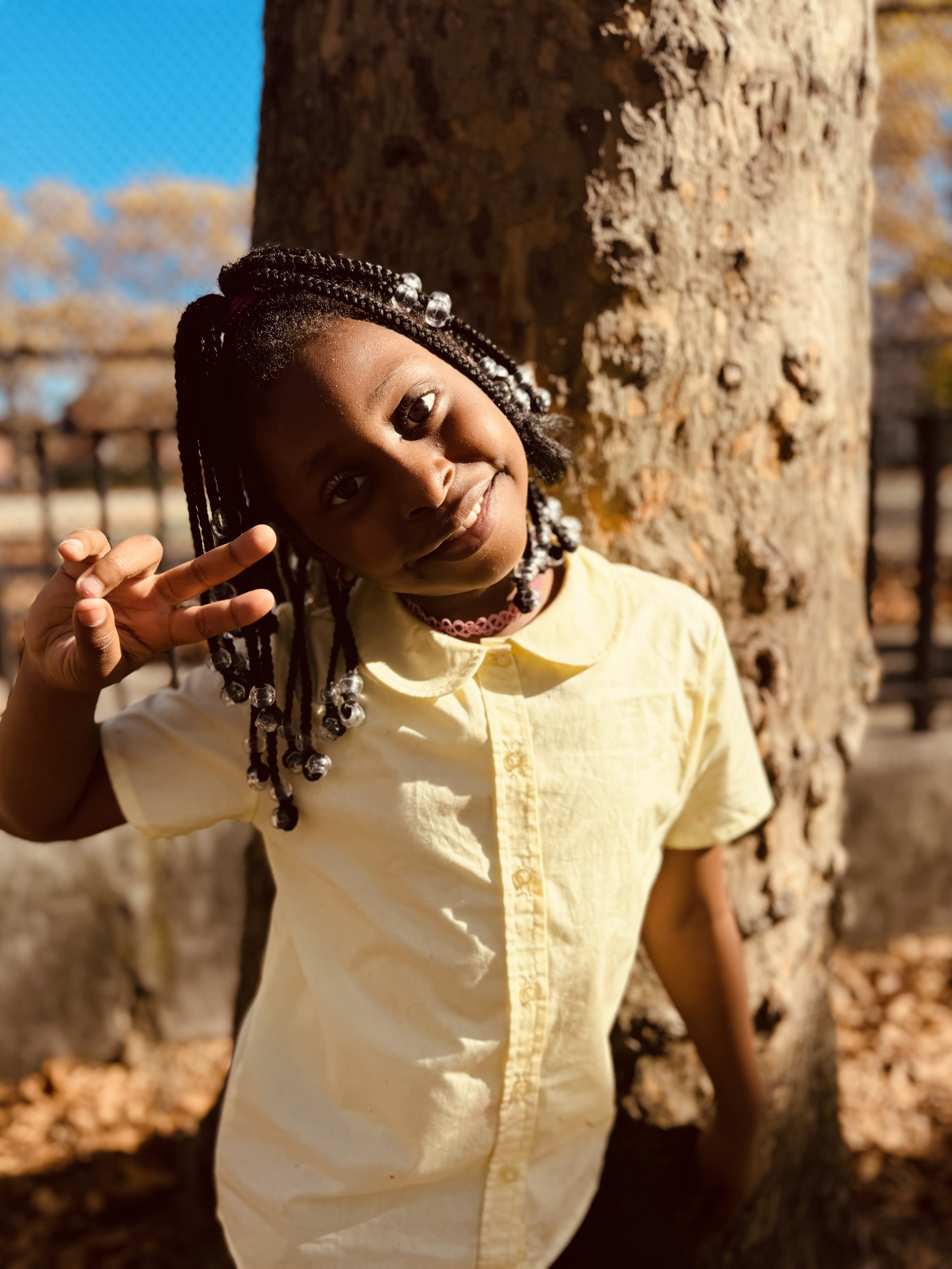 Student smiling and posing outdoors near a tree in fall