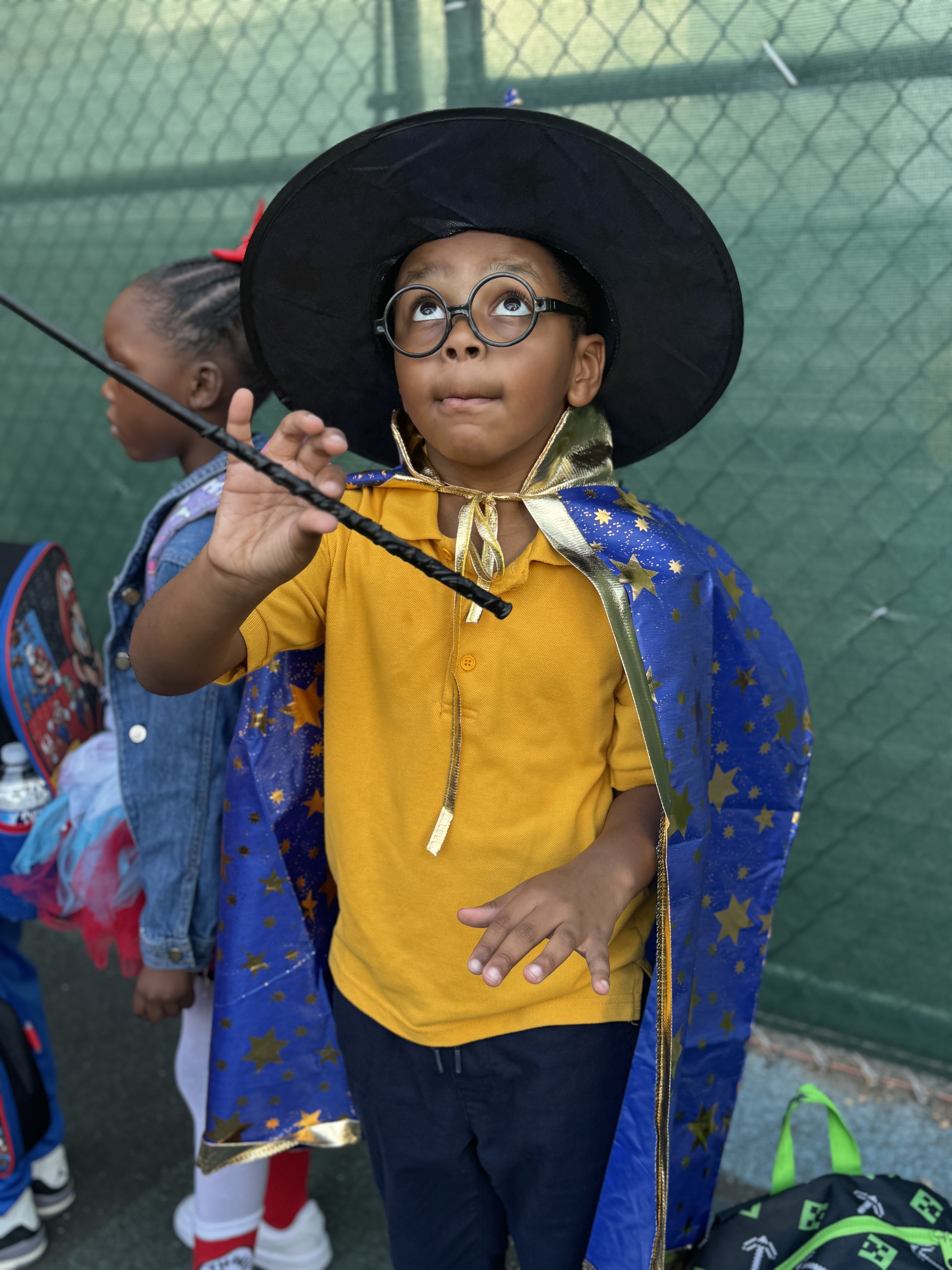 Student in wizard costume holding a wand at school Halloween event