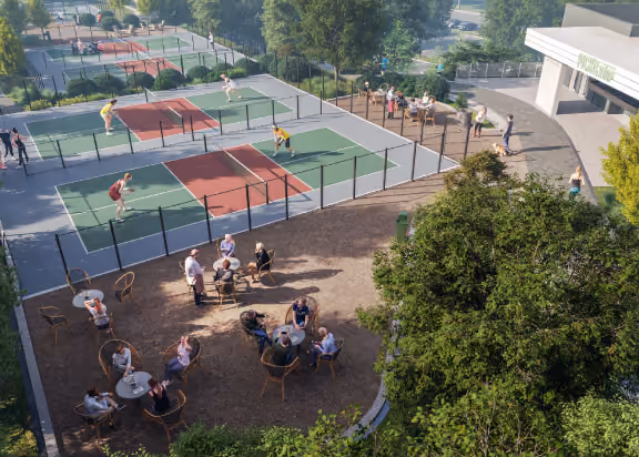 People playing pickleball on the courts with spectators sitting at tables