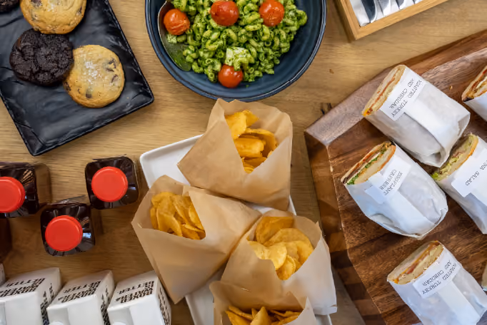 Pesto pasta in a bowl next to bags of chips