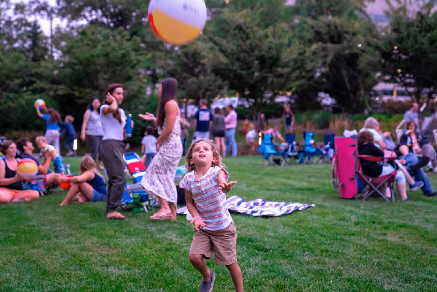 A young child playing with a ball on the grass