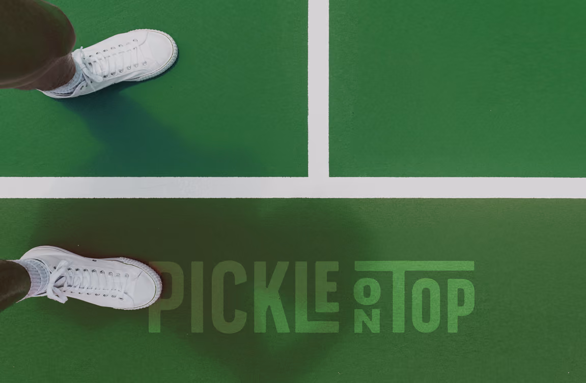 Someone's two feet standing on Pickle On Top's branded court