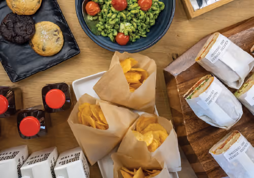 Sandwiches, pesto pasta, cookies and chips on trays for caterig