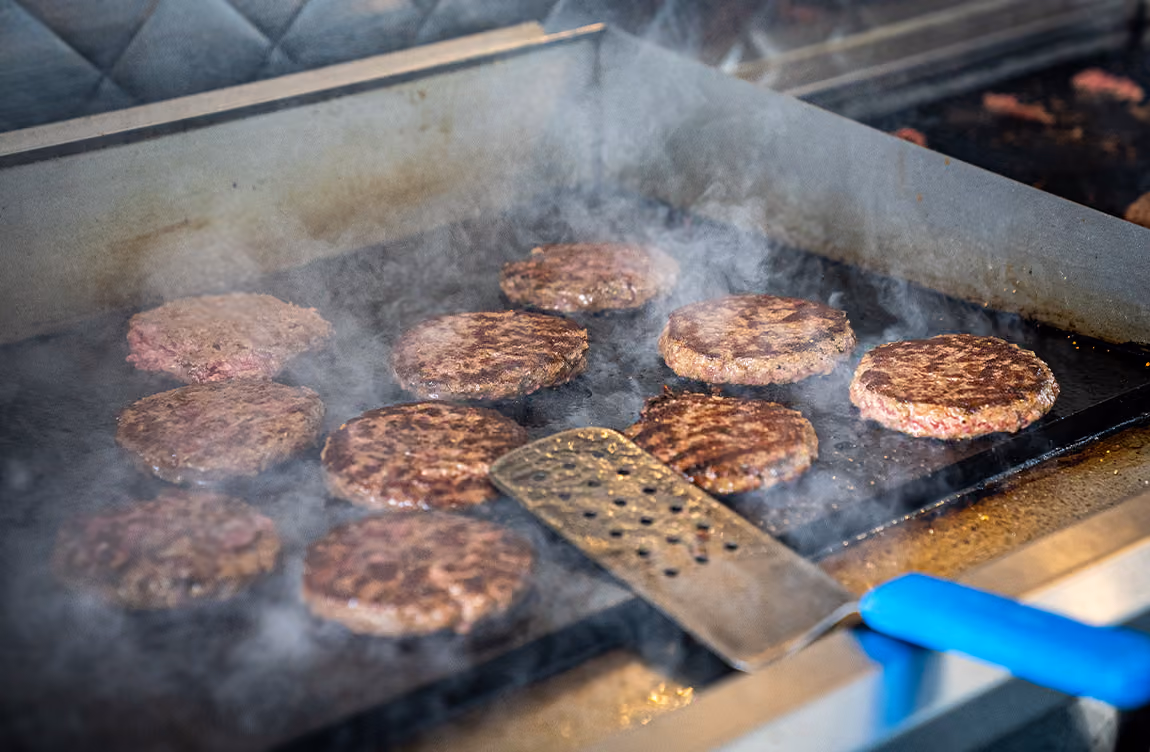 Hamburgers being cooked on a flat top grill