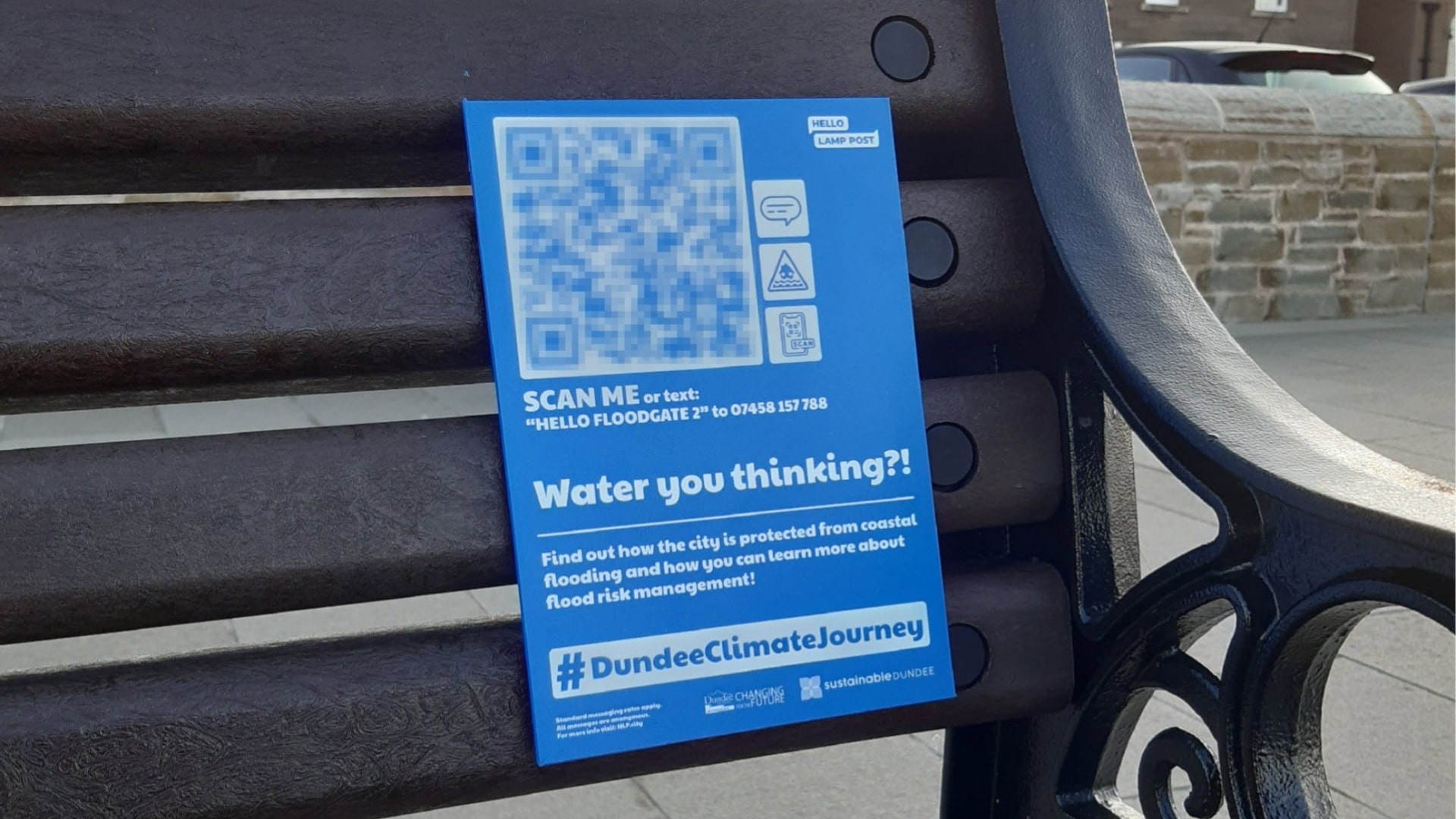 Interactive signage on a bench asking Dundee residents to scan the QR code to chat about coastal flooding and flood risk management