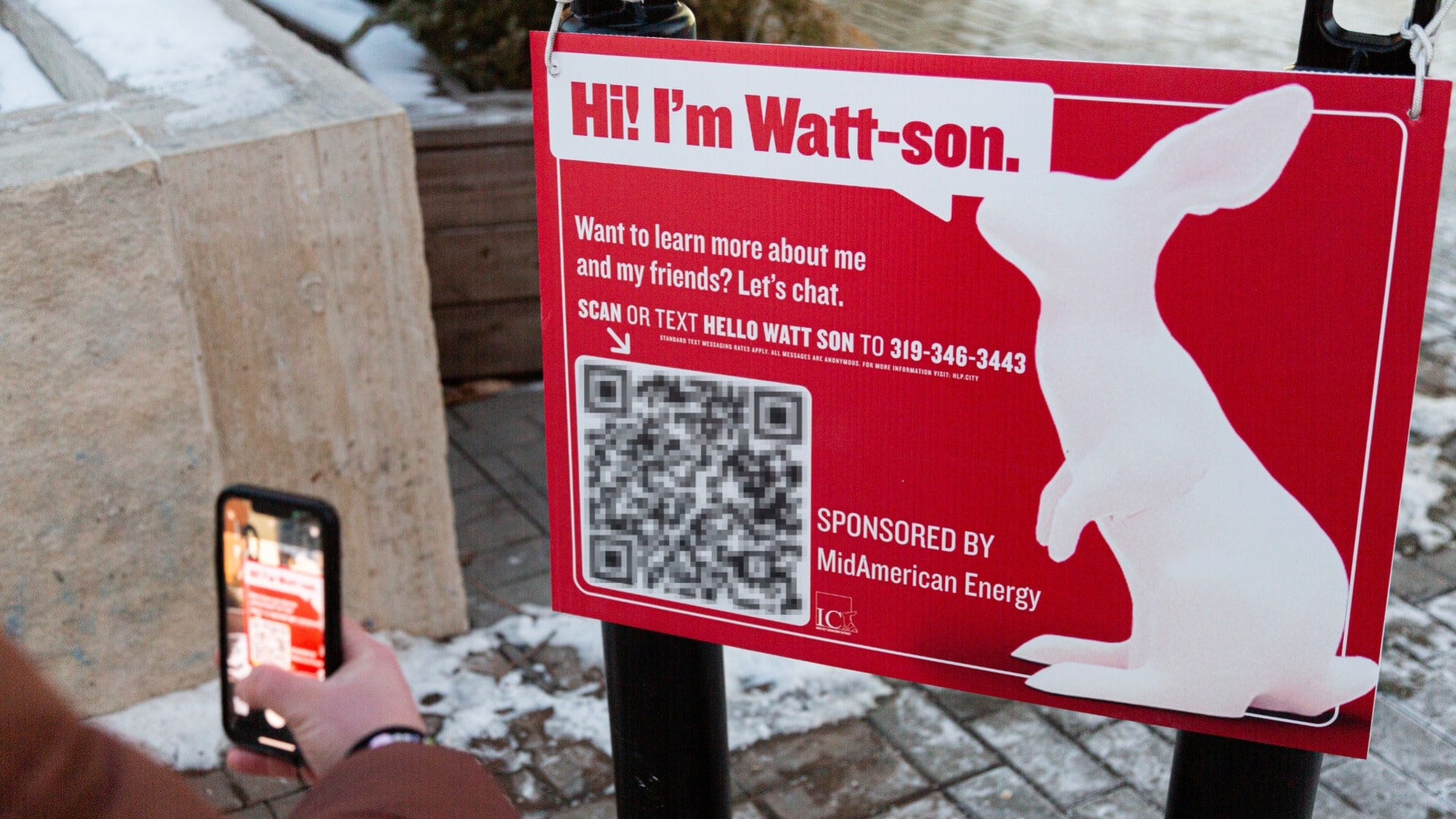 Person using phone to scan QR code to engage with rabbit art installation in Downtown Iowa