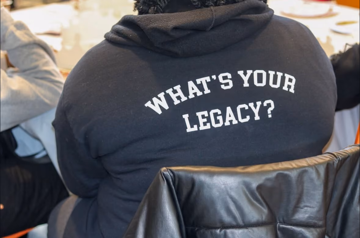 Student wearing hoodie reading What's Your Legacy at school event