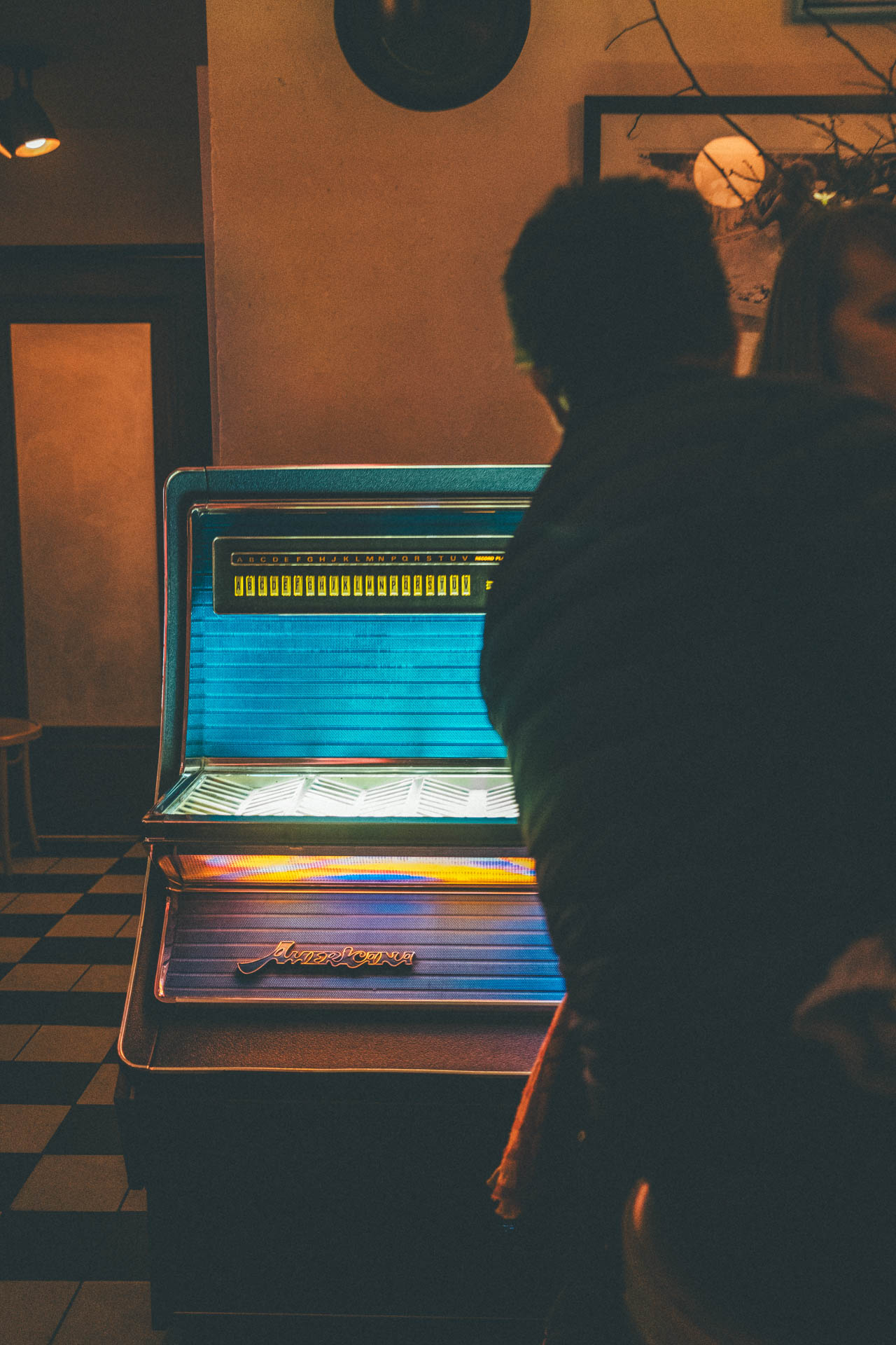 Man in front of a colorful jukebox at a bar at night