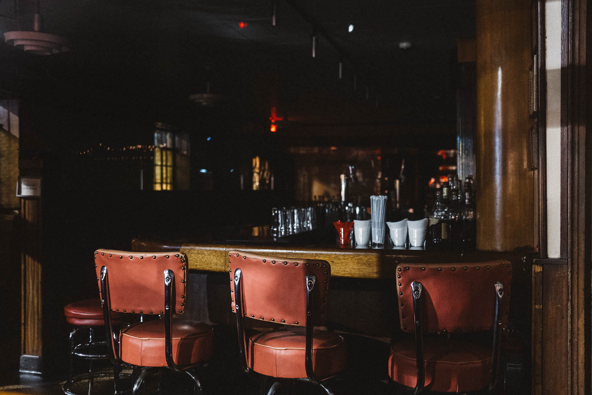 Three bar stools in a dark and closed bar