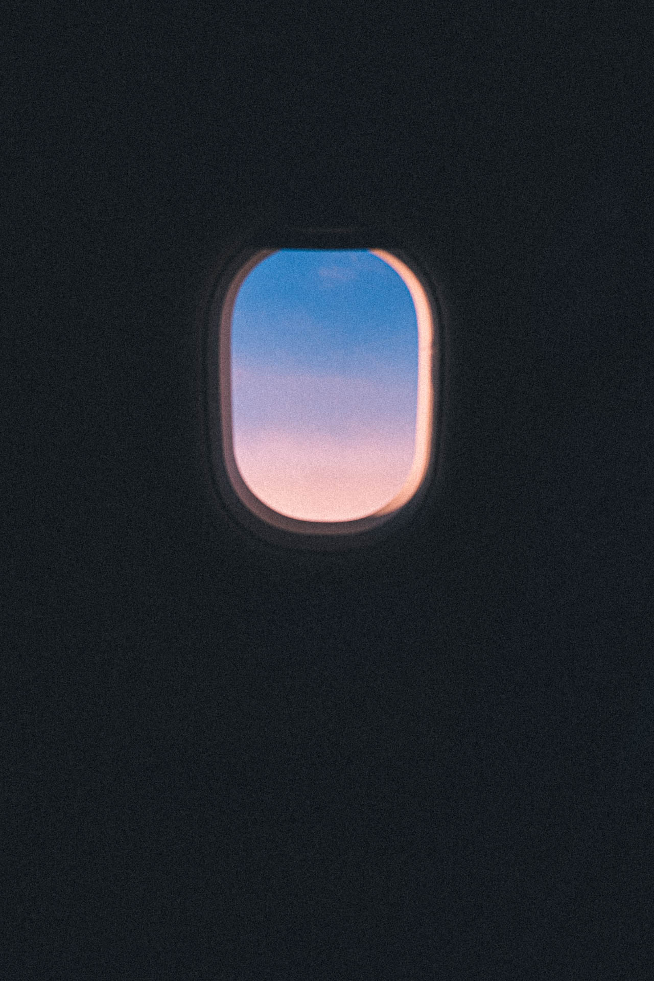 pink and purple sunrise through a plane window