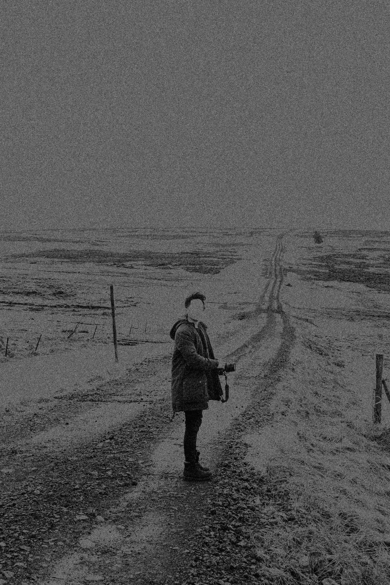 faceless man standing on a long stretch of road in Iceland