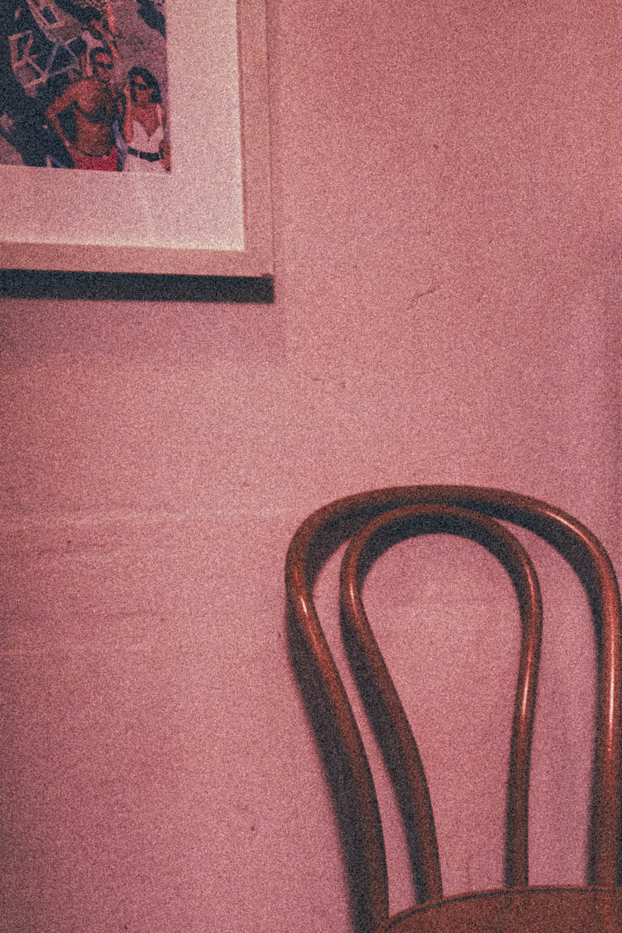 a chair in a pink room under a photo of a couple on vacation