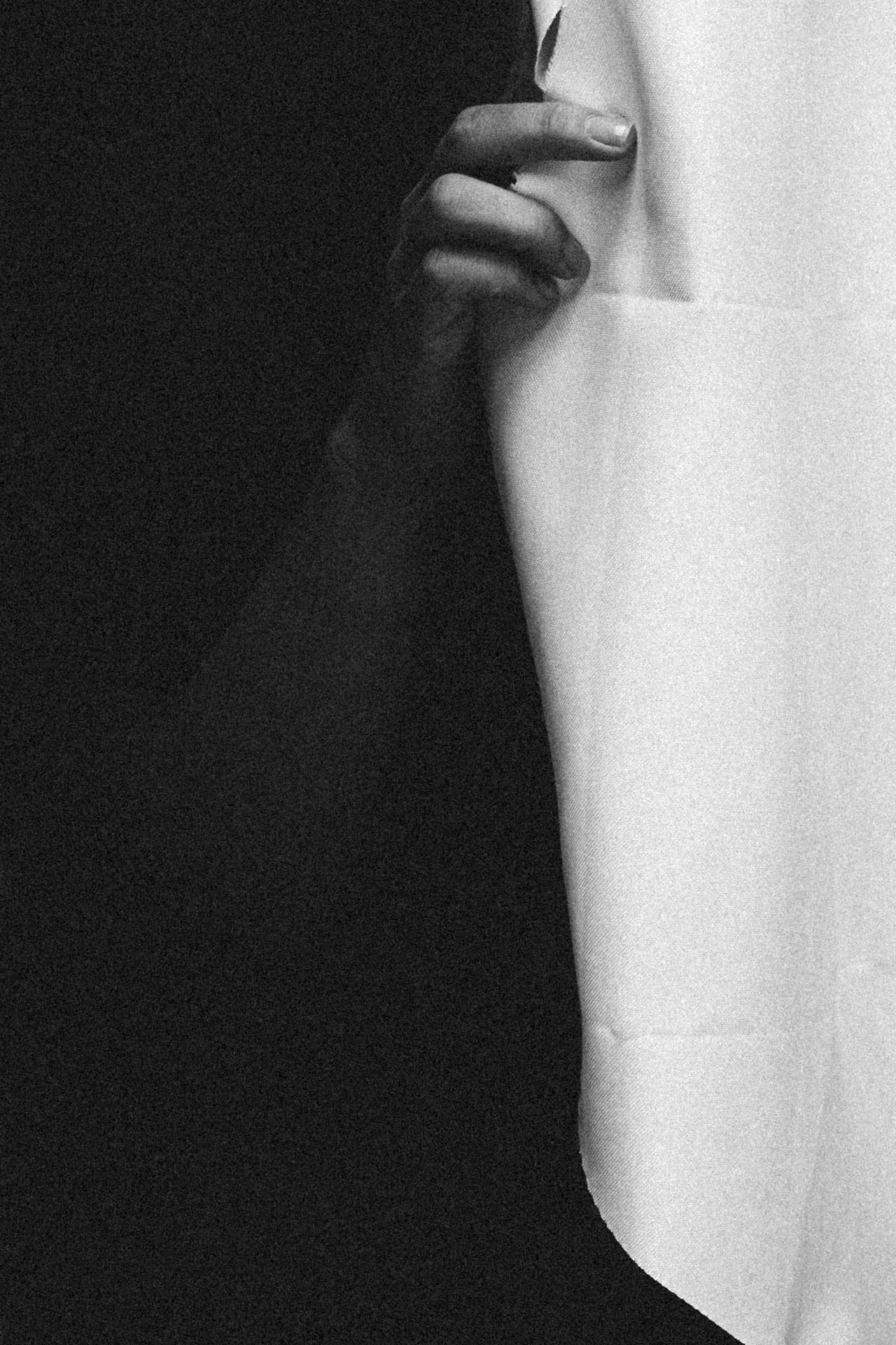 hand holding open a window curtain