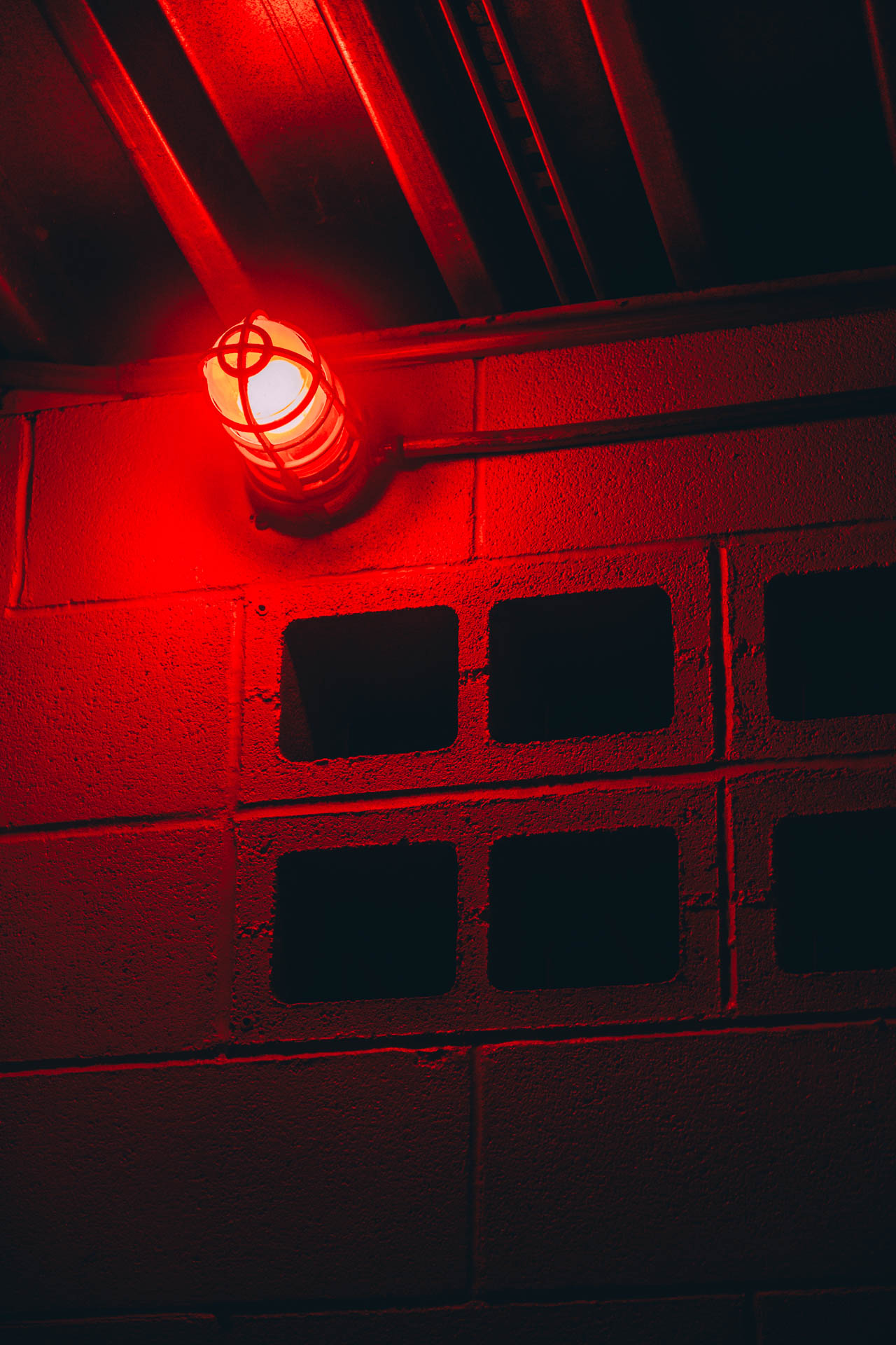 a red light lighting up breeze blocks in a bathroom at night