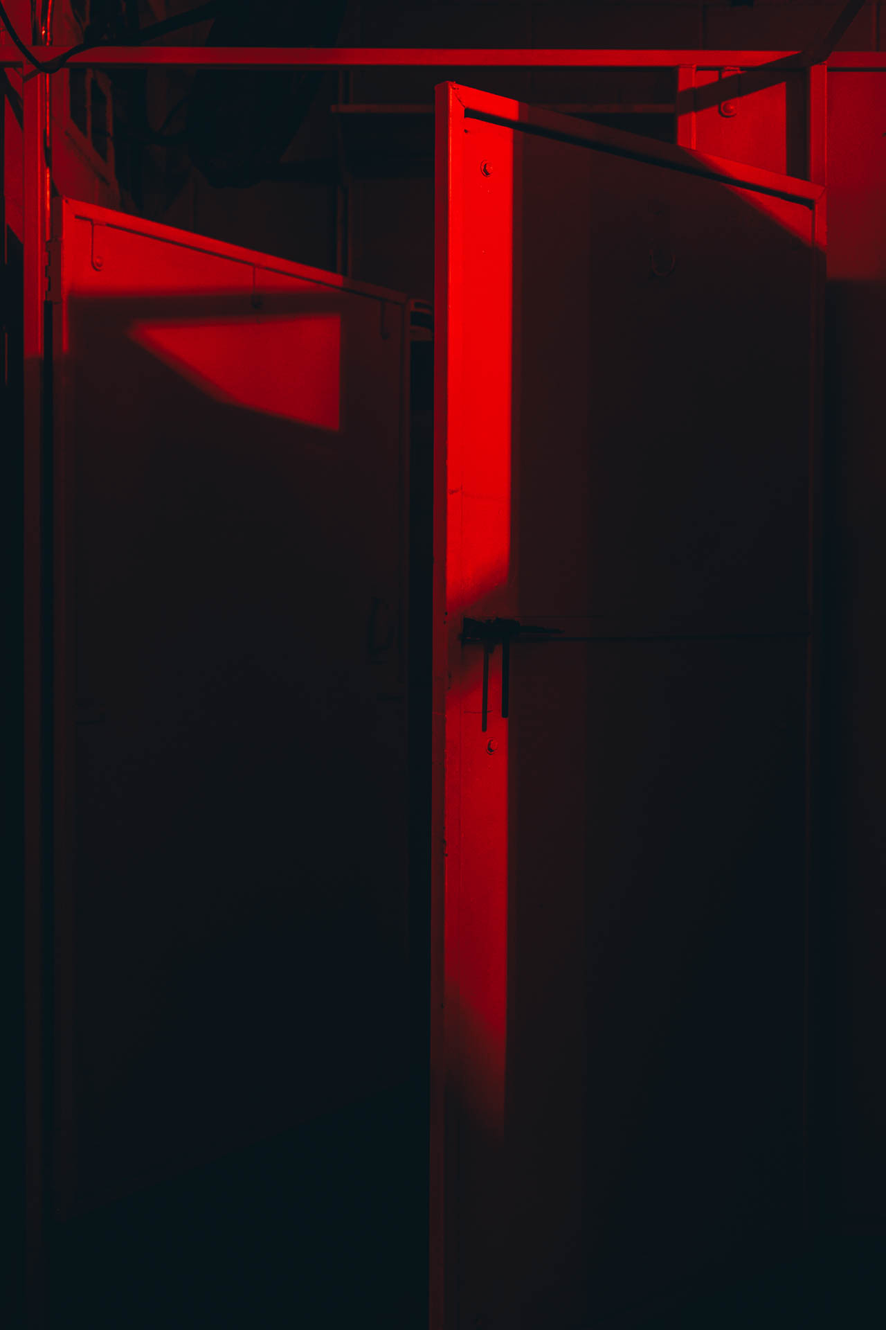 a slightly open bathroom stall in a red lit bathroom at night