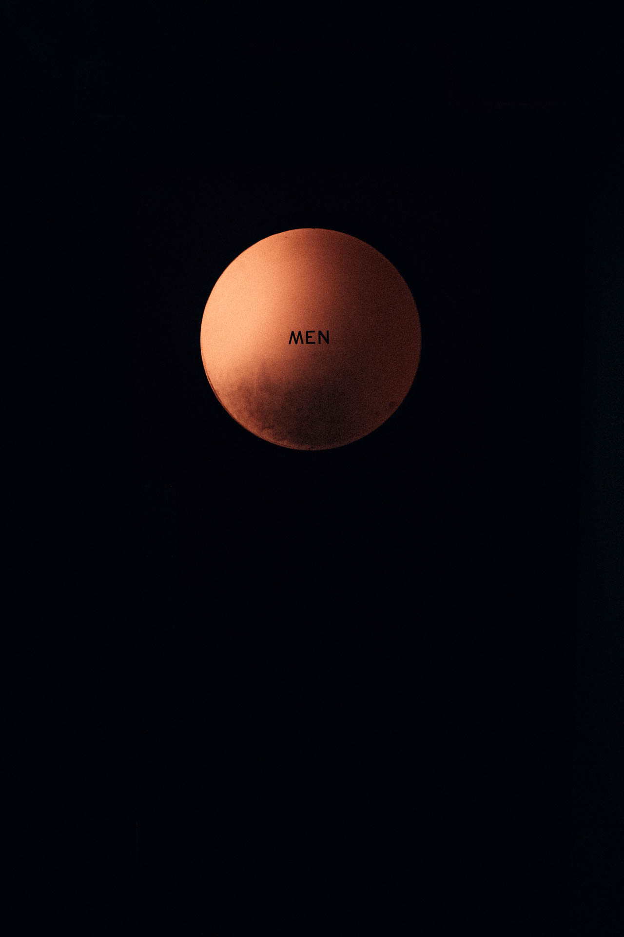mens sign on a bathroom door that looks like a moon