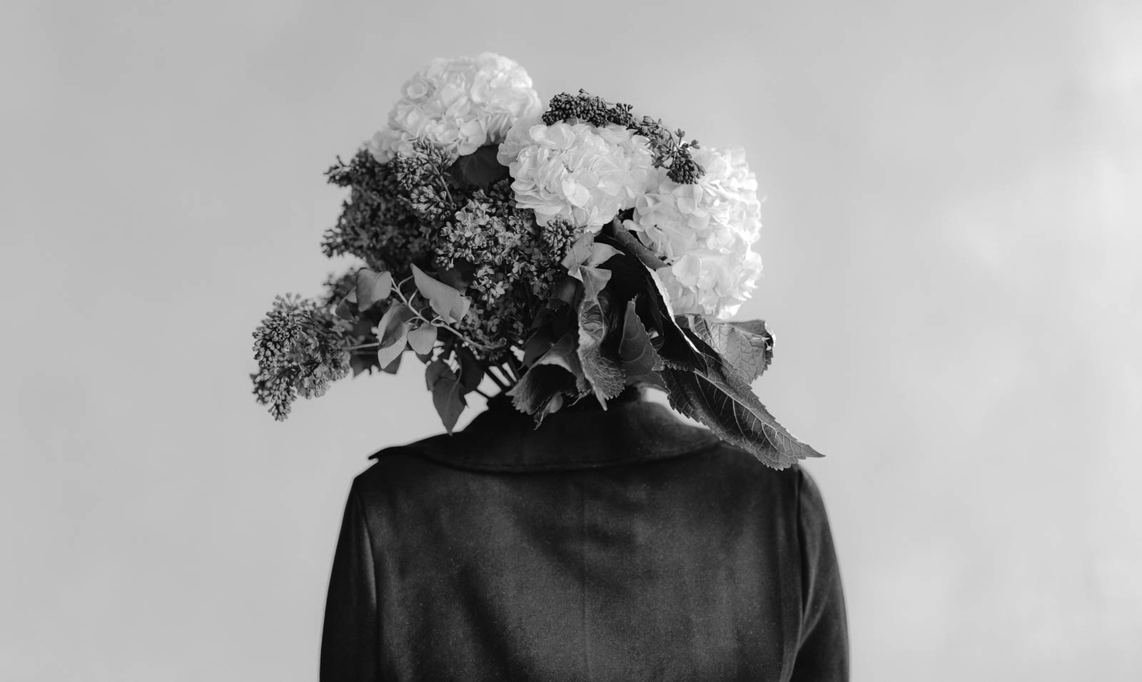person with lilacs and hydrangea flower bouquet for a head in black and white