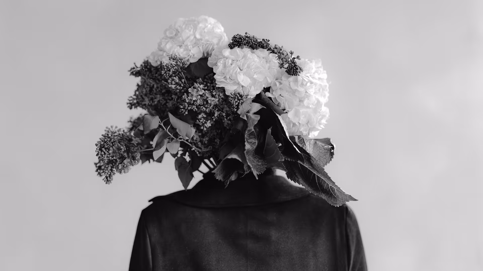 person with lilacs and hydrangea flower bouquet for a head in black and white