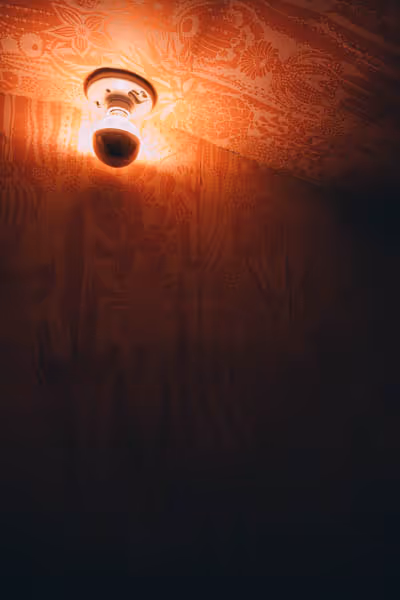 a single light in a bathroom with orange walls